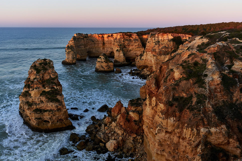 The image shows a photograph of faint sunlight on cliffs of the coast of the Algarve (Portugal).