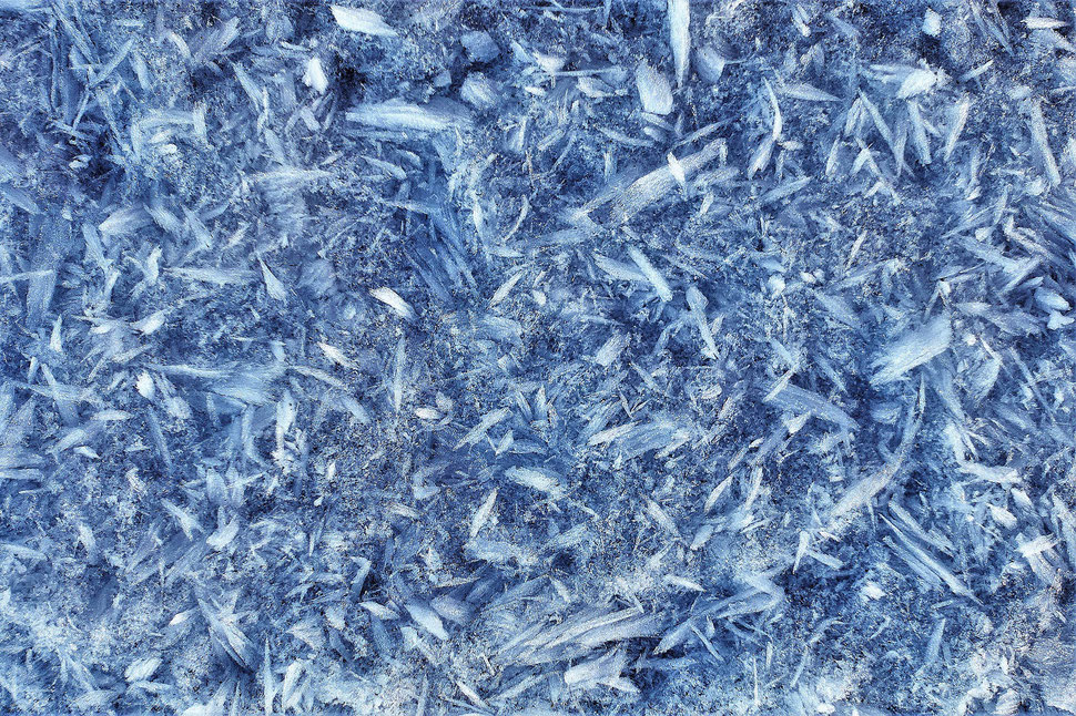 The image shows a high contrast macro photograph of snow and ice crystals.