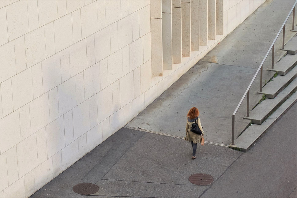 The image shows the aerial photograph of a walking woman in an urban environment. 