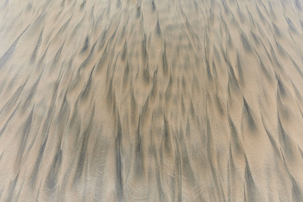 The images shows the photograph of sand structures and patterns on a beach in Ghana.