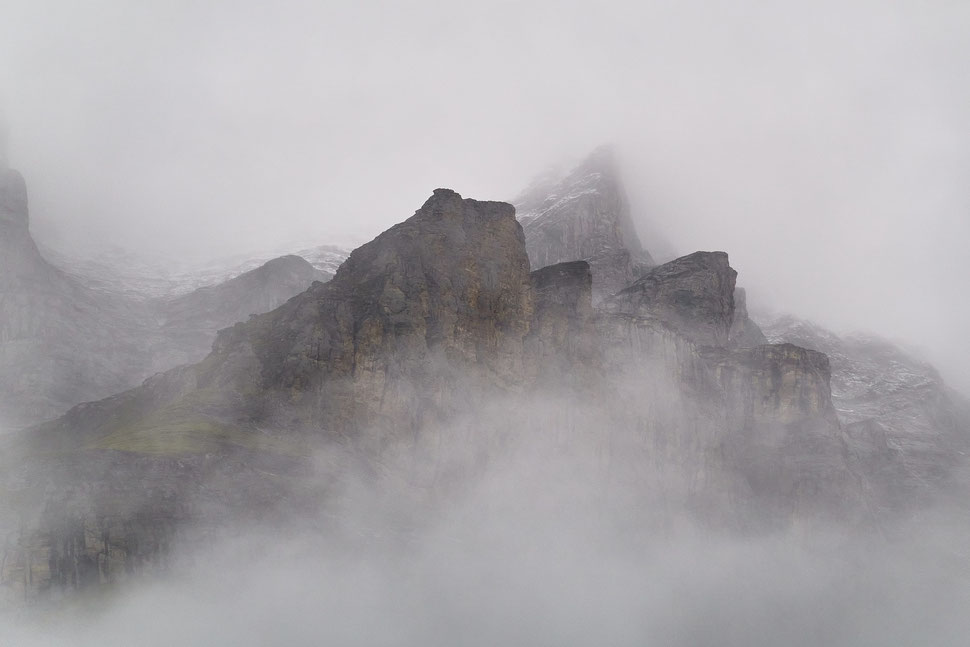 The image shows a photograph of mountains peaks (rocks) rising out of fog. The mood is mysterious.