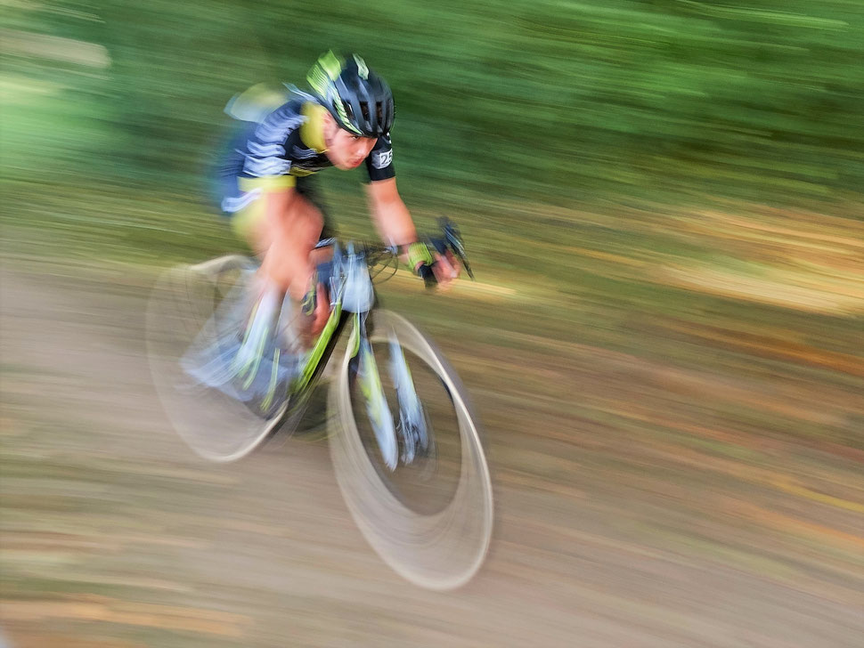 The image shows the photograph of a blurred cyclo-cross racer in full speed.