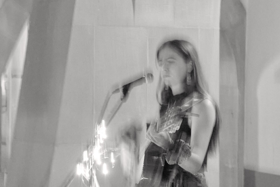 The image shows the black and white photograph of a young female singer performing at the 2025 Buskers Bern. The portrait is blurred.