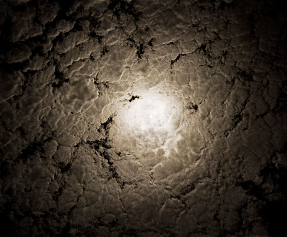 Nous regardons le ciel de nuit sur fond noir avec des nuages formant un tourbillon, une lune au centre éclaire cette surface ressemblant à un vieux cuir d'éléphant. #Provence#Art#AyniArt.