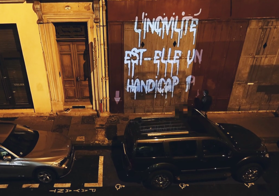 A la nuit tombée vue sur une voiture stationnée dans une ruelle marseillaise, sur un emplacement réservé aux handicapés. Quand le conducteur valide, sort de son véhicule un slogan illumine le mur: "L'incivilité est-elle un handicap"?P. Echaroux & JC Pièri