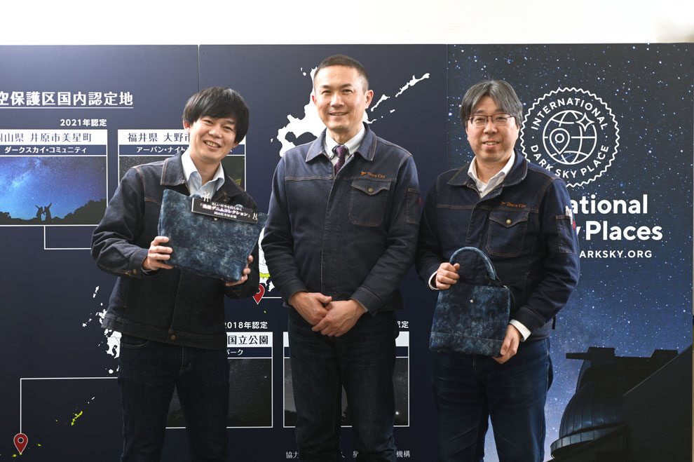 「星空保護区®」の活用に取り組む井原市観光交流課の藤岡健二さん(中央)。小出敏弘さん(右)と磯村有紀さん(左)が手にするのは「星空を持ち歩く」をコンセプトにした特産品デニムのバッグ