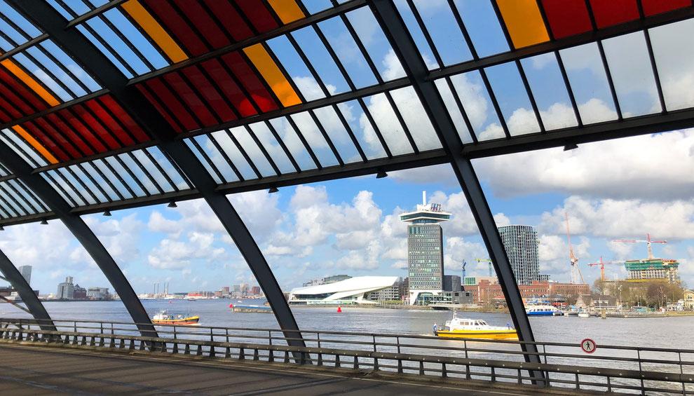 Blick vom Hauptbahnhof (Amsterdam Centraal) auf das IJ, das Filmmuseum Eye und den Amsterdam Toren