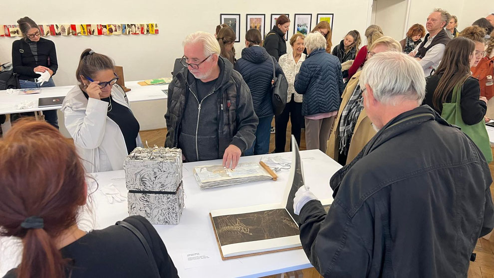 Der Mann hinter dem Tisch hält gerade seine Hand auf meinen Buchkunstbeitrag der Ausstellung. 