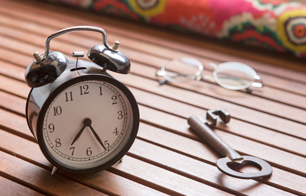 Alarm clock, key and eyeglasses seen over a table of wooden slats on a old house in Assafora, Portugal on 2015