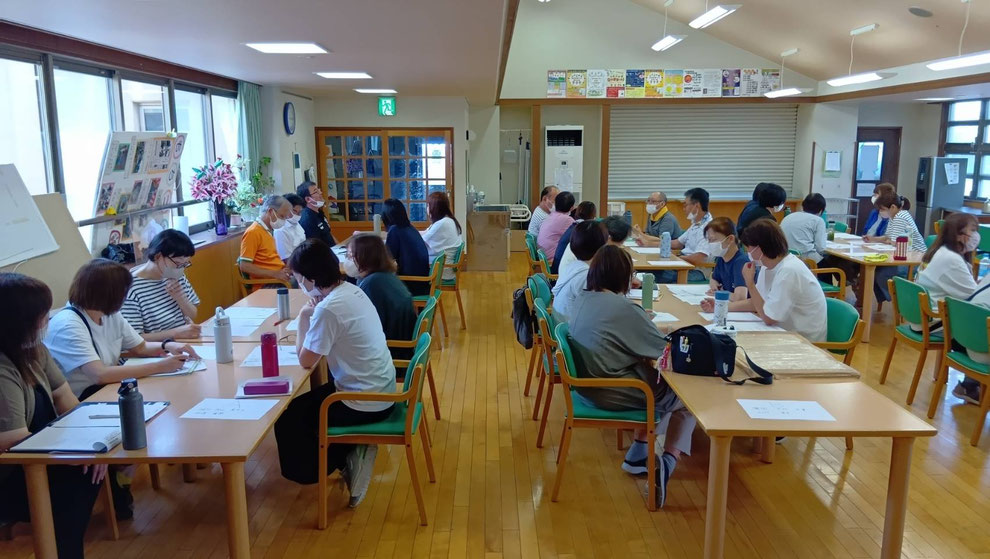 本部食堂での研修の様子。職員が各グループで発表を聞いいている。