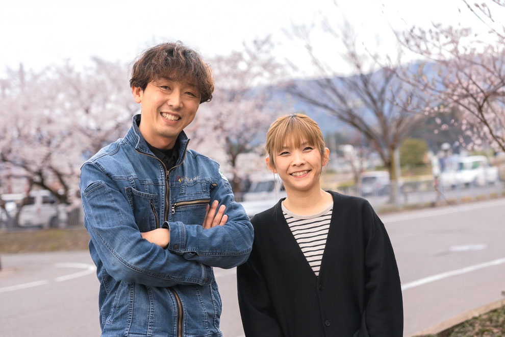 男性従業員と女性従業員が二人仲良くならんで笑っている写真。