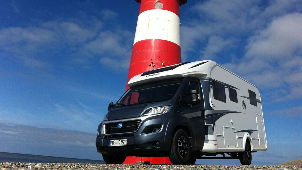 Wohnmobil vor Leuchtturm in Deutschland an der Nordsee-Küste