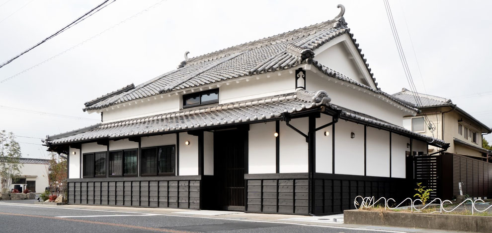 平賀敬一郎建築研究所が設計した、兵庫県福崎町の伝統的木造古民家再生(リノベーション)の外観写真。美しく波打つ日本瓦の屋根と白漆喰壁、腰壁部分の黒い下見板張りが和の情緒を醸し出す、風格ある主屋のファサード。