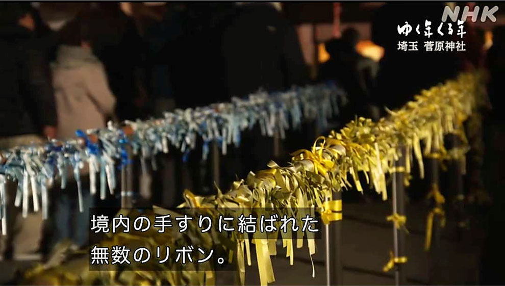「上里菅原神社境内の手すりに結ばれた青と黄色のリボン」 ※NHK『ゆく年くる年』(2025年12月31日)より