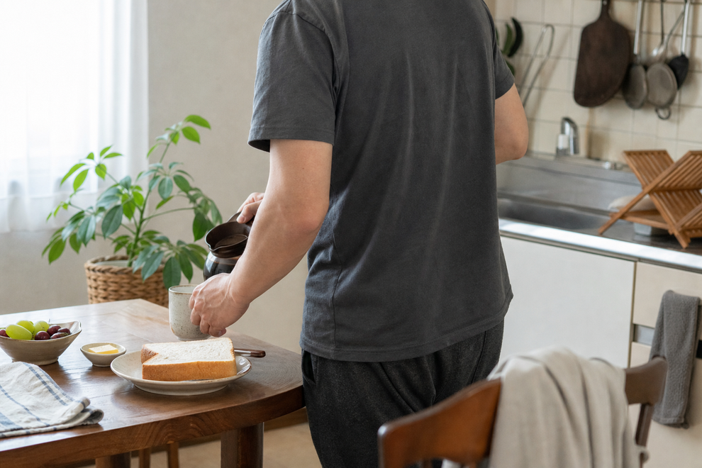 休日の朝に自宅で簡単な朝食とコーヒーを用意する男性の後ろ姿