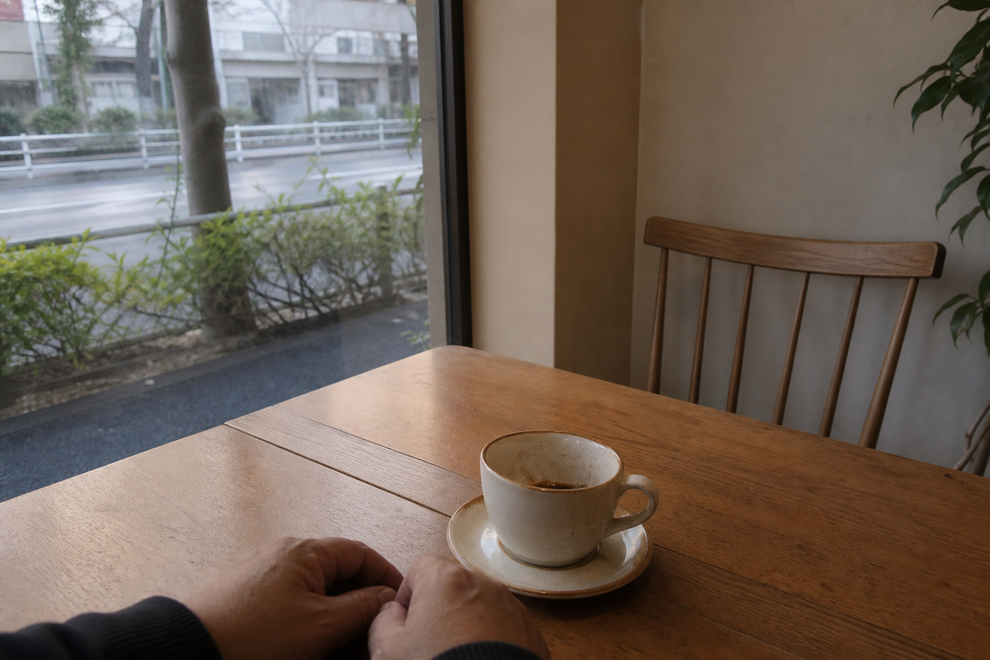 お見合い後の静かなカフェで向かいの空席を見つめる男性の手元