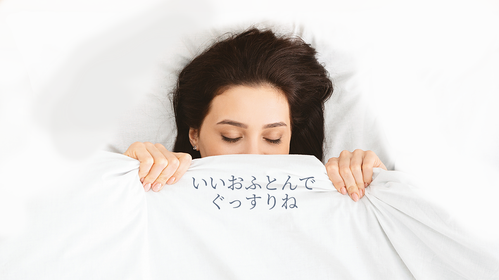 商品案内のイメージ写真　鼻の上まで掛けふとんを引き寄せて眠っている女性　「いいおふとんでぐっすりね」