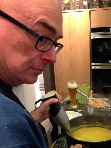 Foto von Raphael Frasch wie er eine Suppe im Kochtopf püriert.