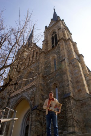 Jounalist Winfried Gburek mit einem Foto der Ausstellung vor dem Pongauer-Dom in St. Johann im Pongau, einem Ausstellungsort der Foto-Reportage