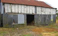Hangar : mur de palis et bardage bois