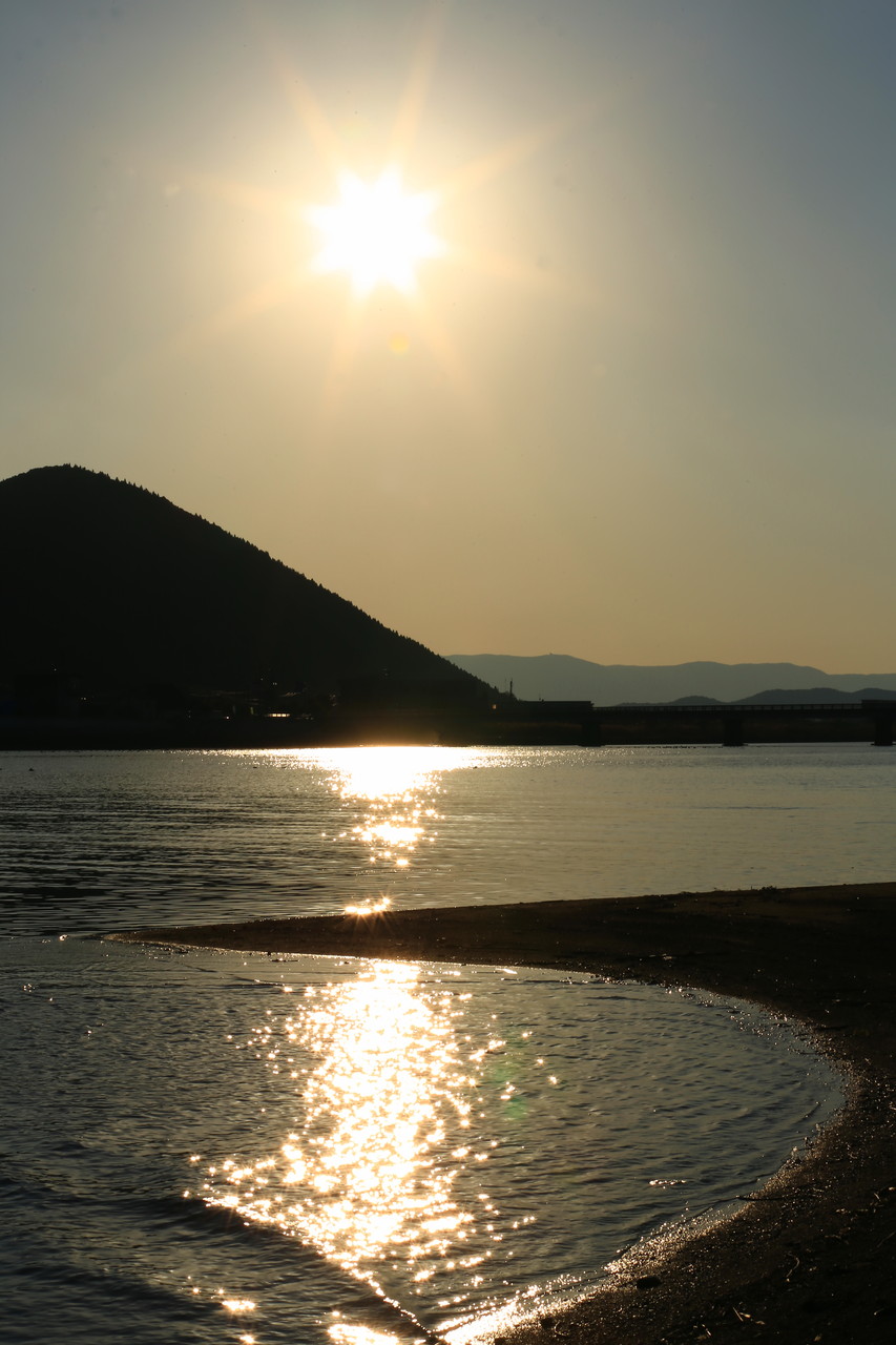 権現山と夕陽の光で煌めく水面（東串良町柏原）