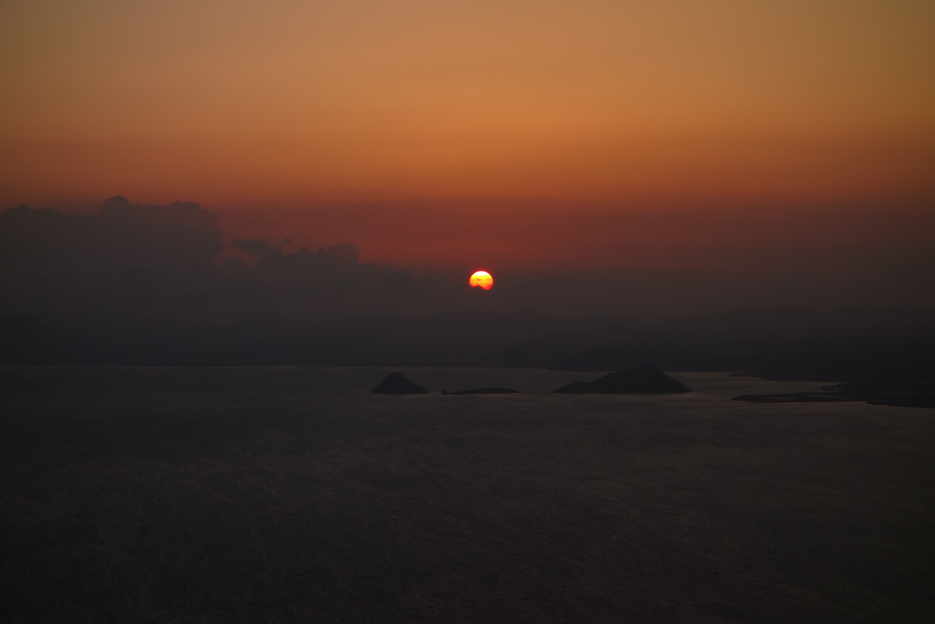 霧島市沖の無人島「神造島」をバックに沈む夕日（アップ）。