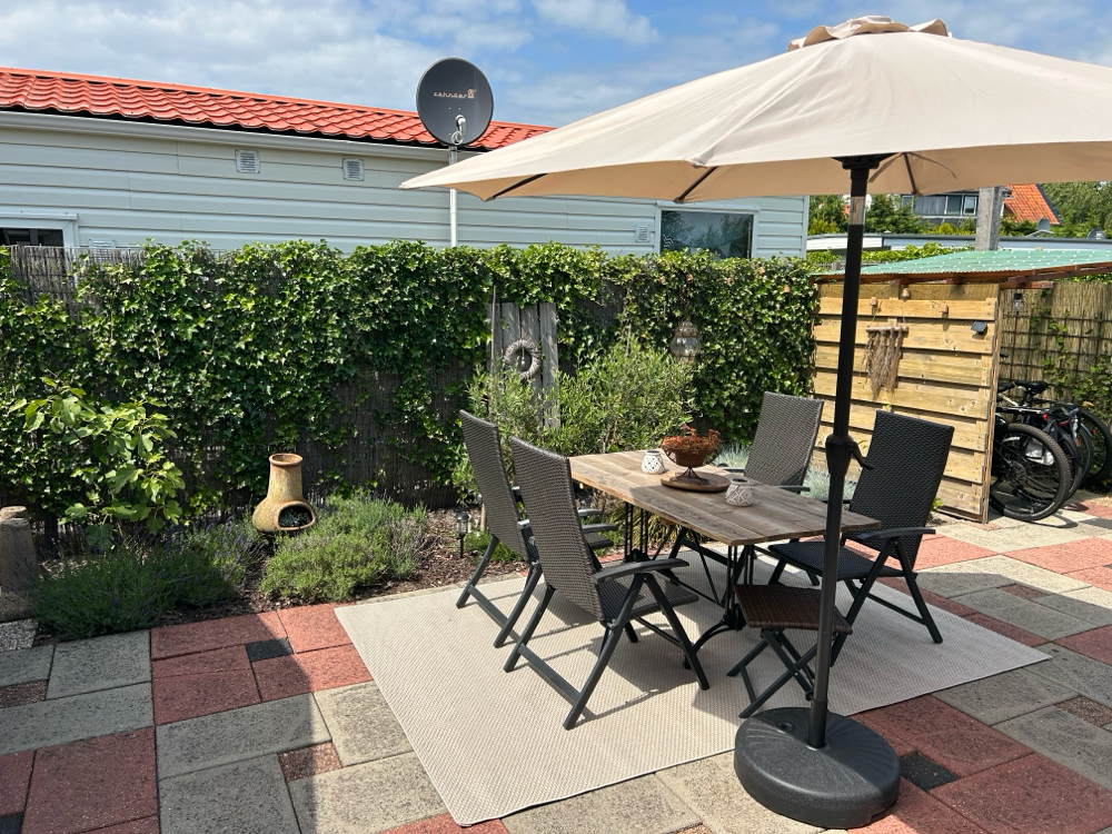Sonnige und sichtgeschützte Terrasse mit schönen und bequemen Sonnenstühlen und großem Holztisch 