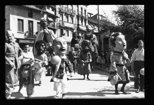 Comparsa de Gigantes y Cabezudos en 1946?/1947? a su paso por la calle Iglesia, apreciándose edificios de la misma ya desaparecidos.