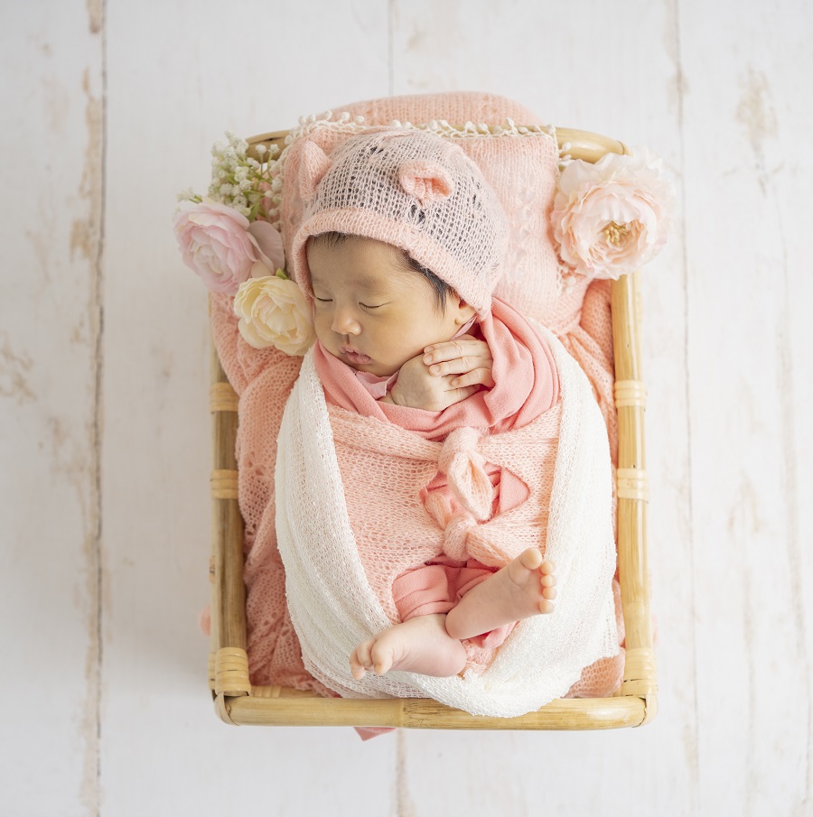 ピンクのおくるみにくるまれている赤ちゃん