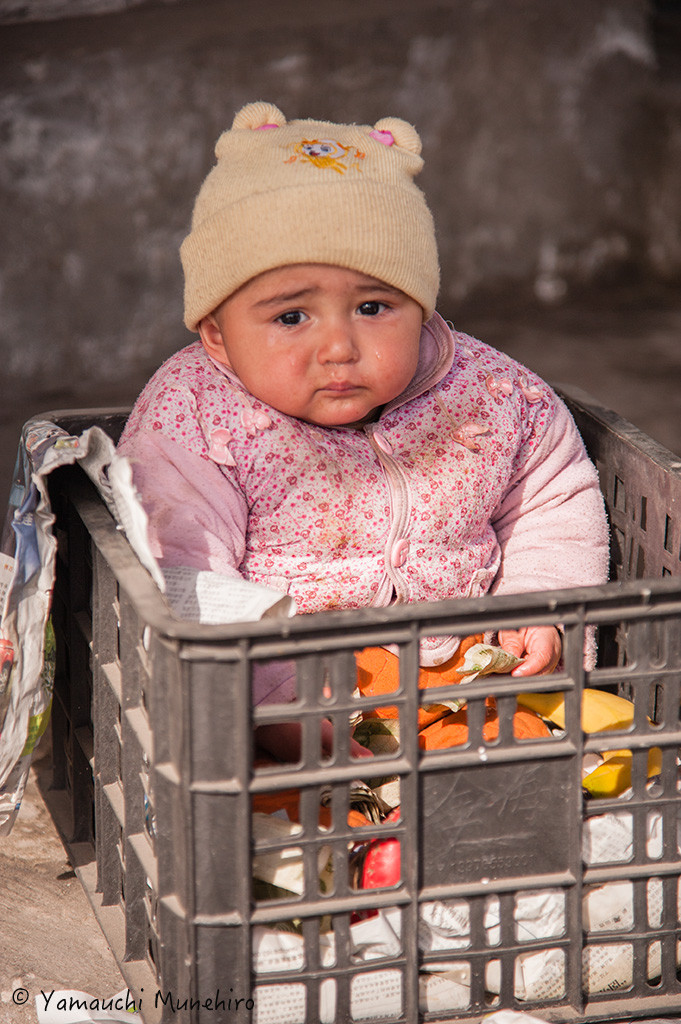 良く見ると泣いているこの赤ちゃんはお札を握りしめています。和田（ホータン） 新疆ウイグル自治区　Hotan　Xinjiang Uyghur Autonomous Region