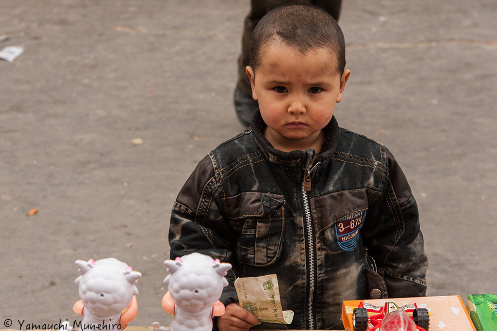 この子もオモチャを前にお札を握りしめてます。それにしてもこの歳でこのハードボイルド感。只者じゃない。和田（ホータン） 新疆ウイグル自治区　Hotan　Xinjiang Uyghur Autonomous Region
