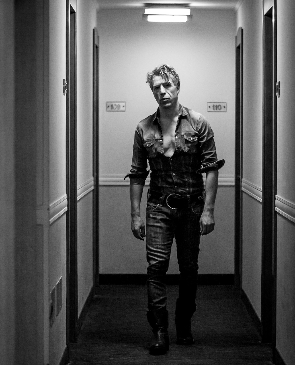 Ottaviano Blitch, Italian actor and performer, cinematic full-length portrait at the end of a corridor with dramatic perspective lighting, attore performer italiano ritratto cinematografico corridoio