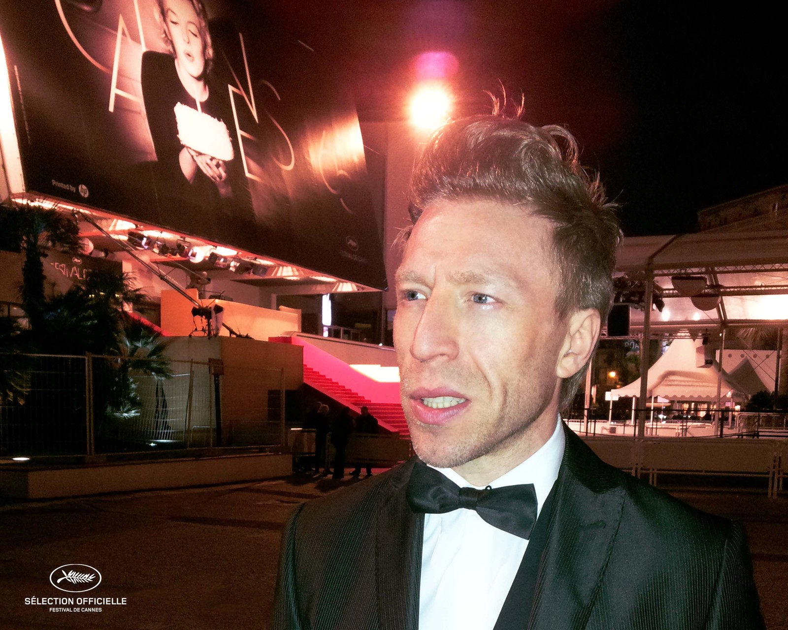 Ottaviano Blitch, Italian actor and performer, cinematic night portrait in a tuxedo on a neon-lit city street, attore performer italiano ritratto notturno Festival de Cannes outside the Croisette