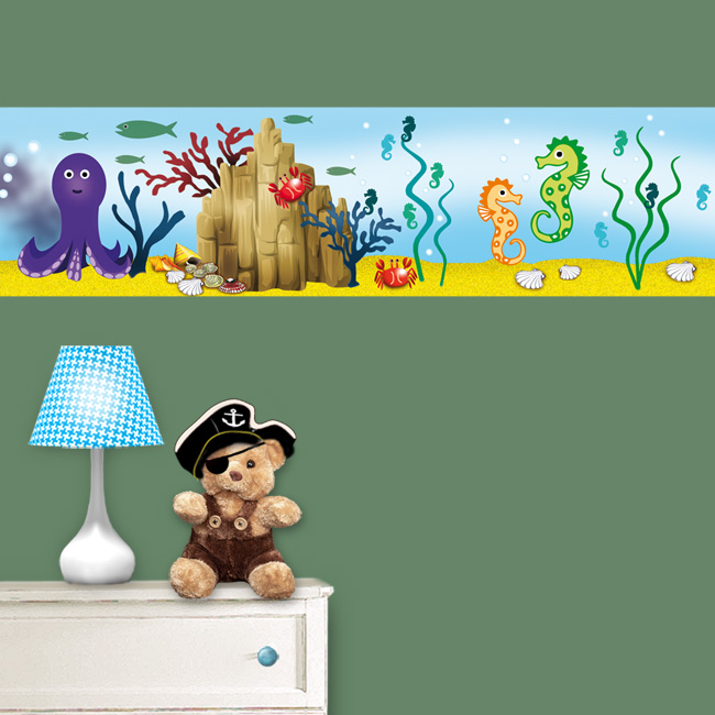 Unterwasserwelt-Bordüre an einer grünen Wand über einer weißen Kommode mit einem Teddybären im Piraten-Look.