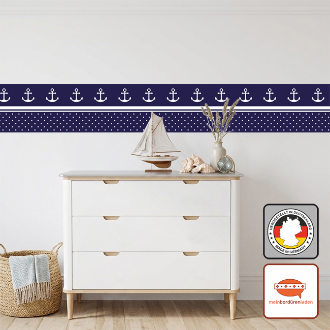 Dunkelblaue Anker-Bordüre an einer weißen Wand über einer hellen Holzkommode mit Deko-Schiff.