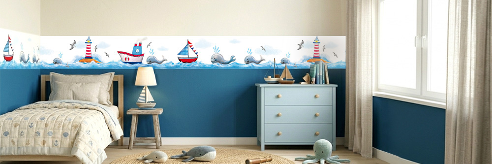 Ein maritim eingerichtetes Kinderzimmer mit einer handgemalten Wandbordüre - Wale, Leuchttürme und Schiffe auf dem Meer.