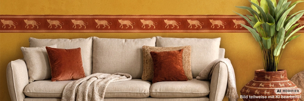 Wohnzimmer mit beigem Sofa und einer weinroten Ethno-Wandbordüre, die goldene Leoparden auf ockerfarbener Wand zeigt.