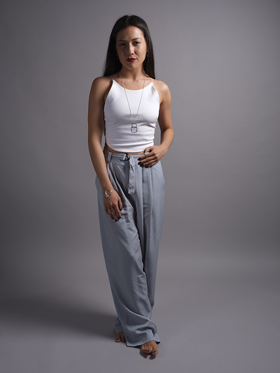 jeune femme debout en top blanc et pantalon large bleu portant un long sautoir et un bracelet en argent recyclé de la collection Quadra