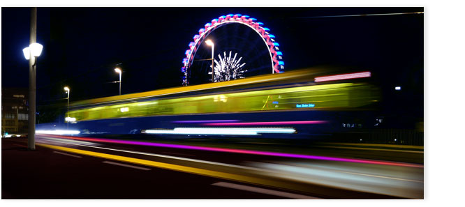 Tram auf Quaibrücke mit Riesenrad im Hintergrund