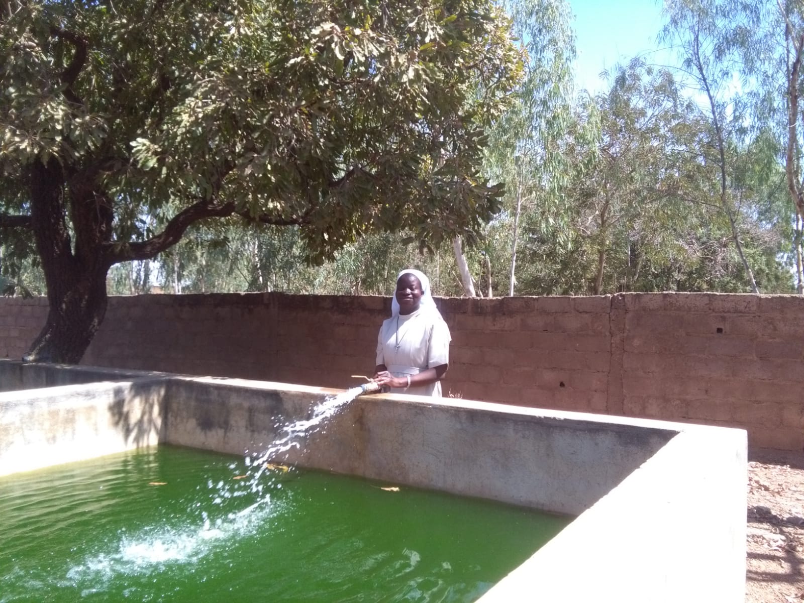 Schwester Lucie beim Auffüllen der Fischbecken.