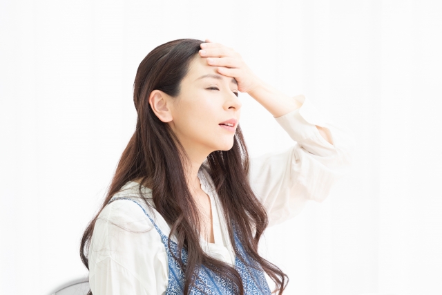 おでこに手を当てる女性
