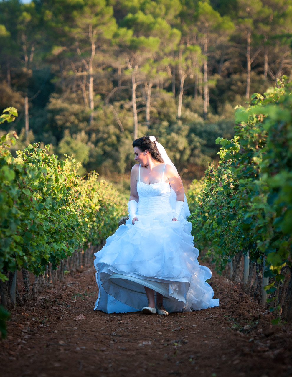 Mariée courant dans les vignes avec sa robe blanche