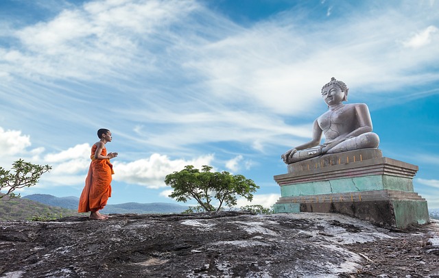 Ein Meditierender vor einer Statue eines meditierenden Buddha