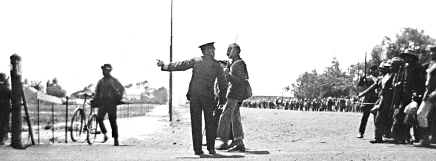 Policeman confronting Mahatma Gandhi as he led the striking Indian mineworkers from Newcastle to the Transvaal (in protest of the Immigration Act), November 6, 1913.