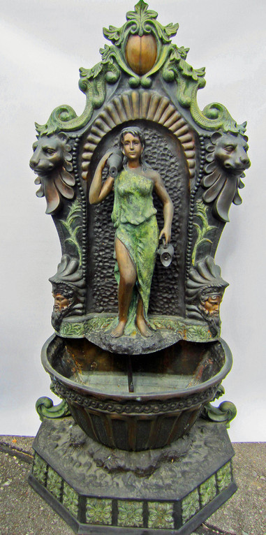 Wunderschöner Jungendstil-Brunnen mit der Darstellung einer Frau mit Krug.  Zu den weiteren Kunst-Details des Brunnens gehören die Löwenköpfe und antiker Krieger an den Seiten des Wandbrunnens. Das Wasser spritz bei diesem Brunnen aus den Krügen der Frau.