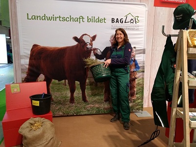 Ruth Kleinöder mit Heu im Korb vor Selfi-Transparent mit Kuh
