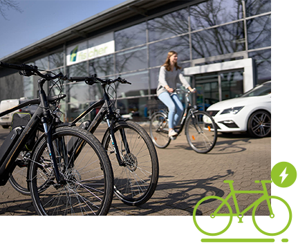 Mitarbeiterin auf E-Bike vor dem Firmengebäude des Autohauses Fischer.