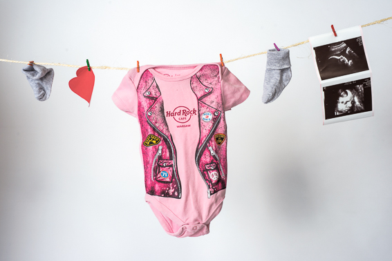 Babybody und kleine Babysachen hängen an einer Leine vor hellem Hintergrund im Studio