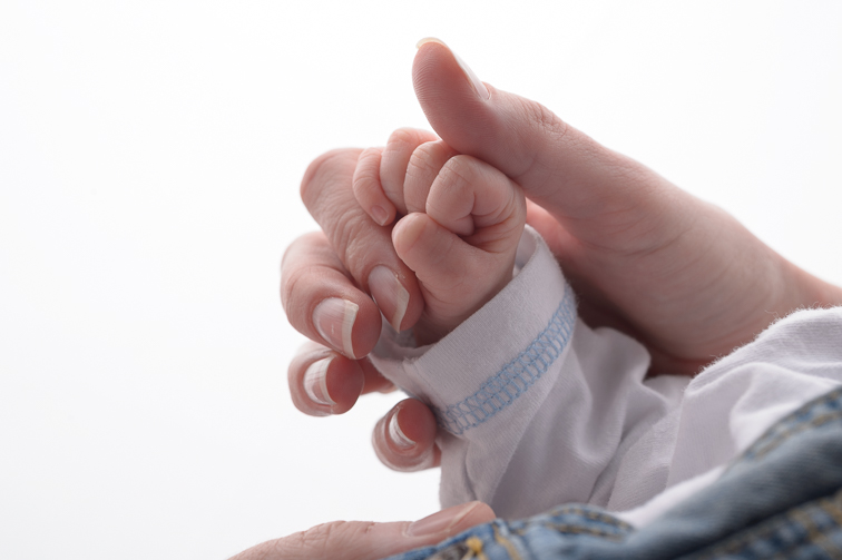 Detailaufnahme einer Babyhand, die einen Finger greift, Babyfotografie in Villach
