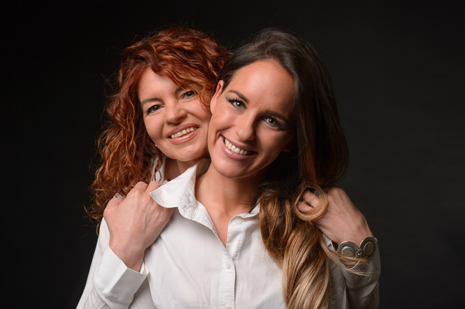 Liebevolles Mutter-Tochter-Foto – zwei Frauen umarmen sich und lächeln herzlich, Studioaufnahme von Hannes Pacheiner in Villach